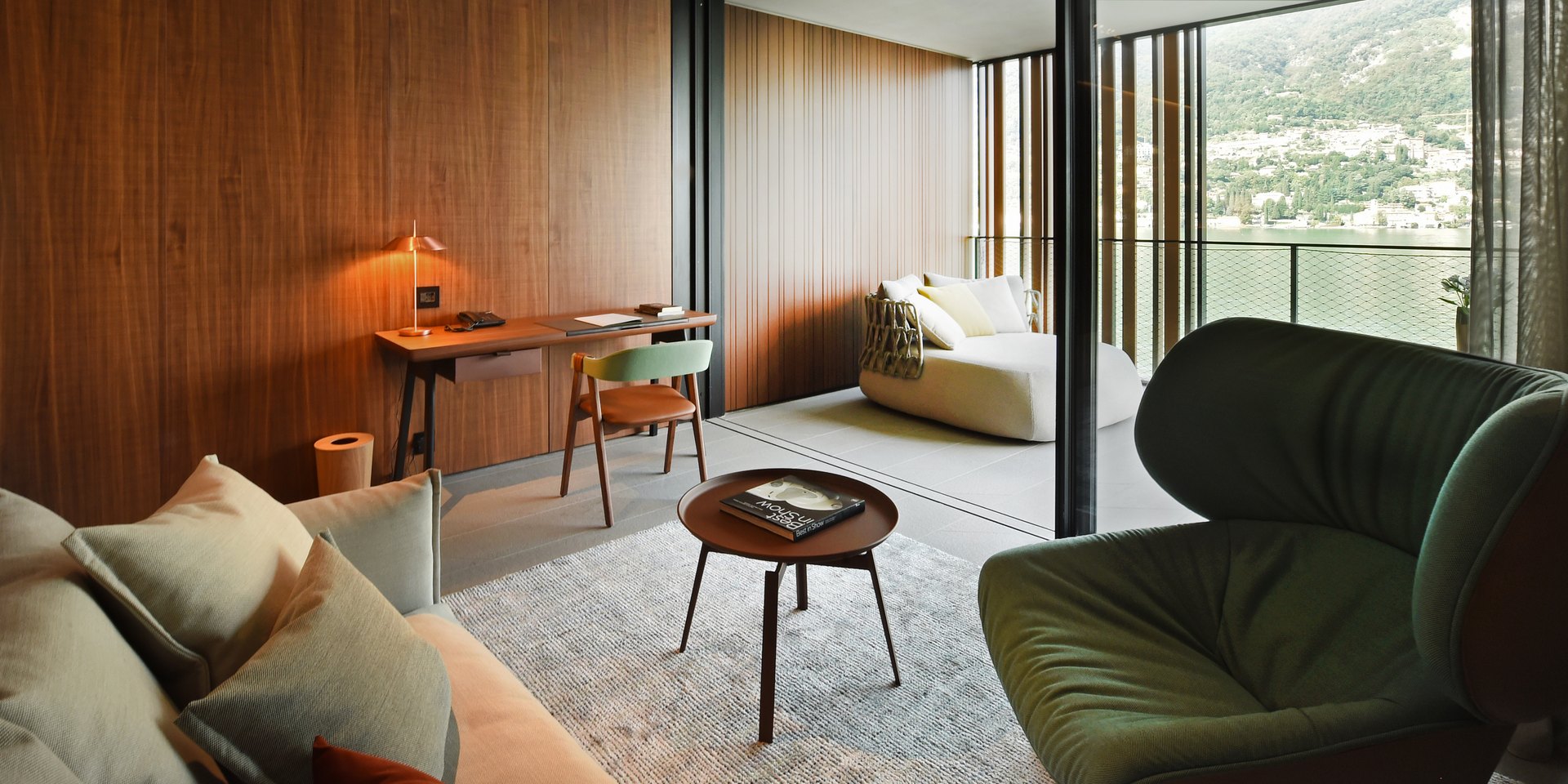 A room at Il Sereno by Patricia Urquiola, with a green armchair and a wall of glass onto the lake