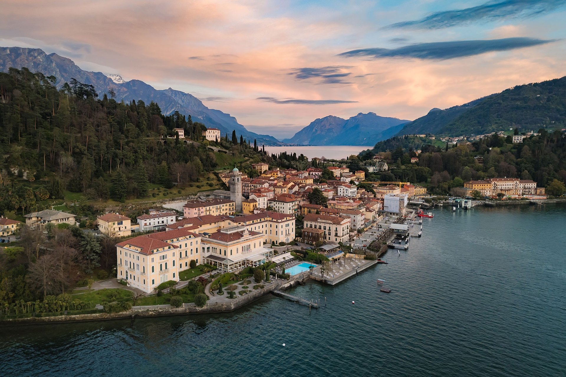 Bellagio at dusk from the air, with the Grand Hotel Villa Serbelloni and its pool at the tip of the peninsula