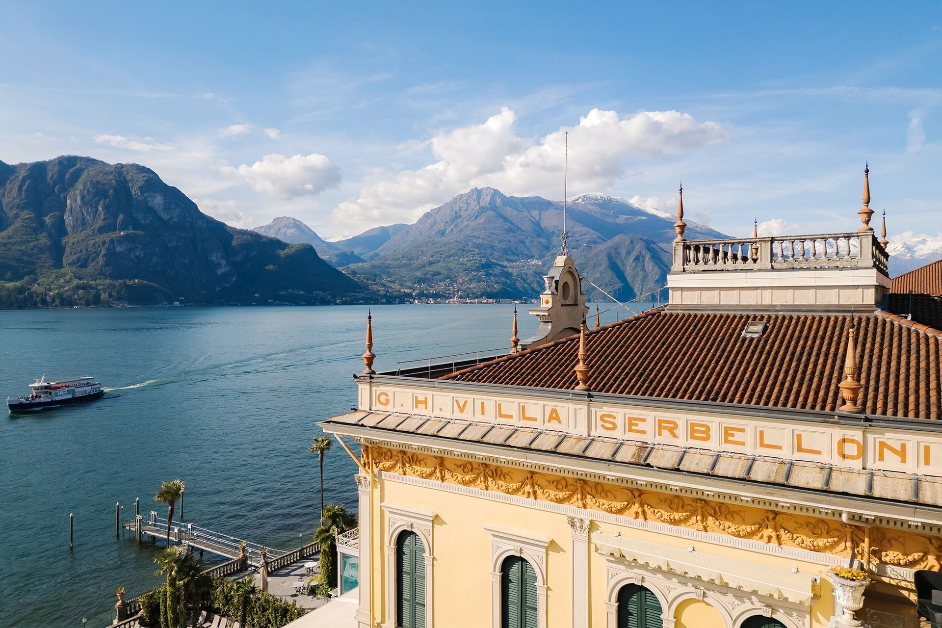 The roof and lettered façade of the Grand Hotel Villa Serbelloni, with a lake steamer and the mountains across the water