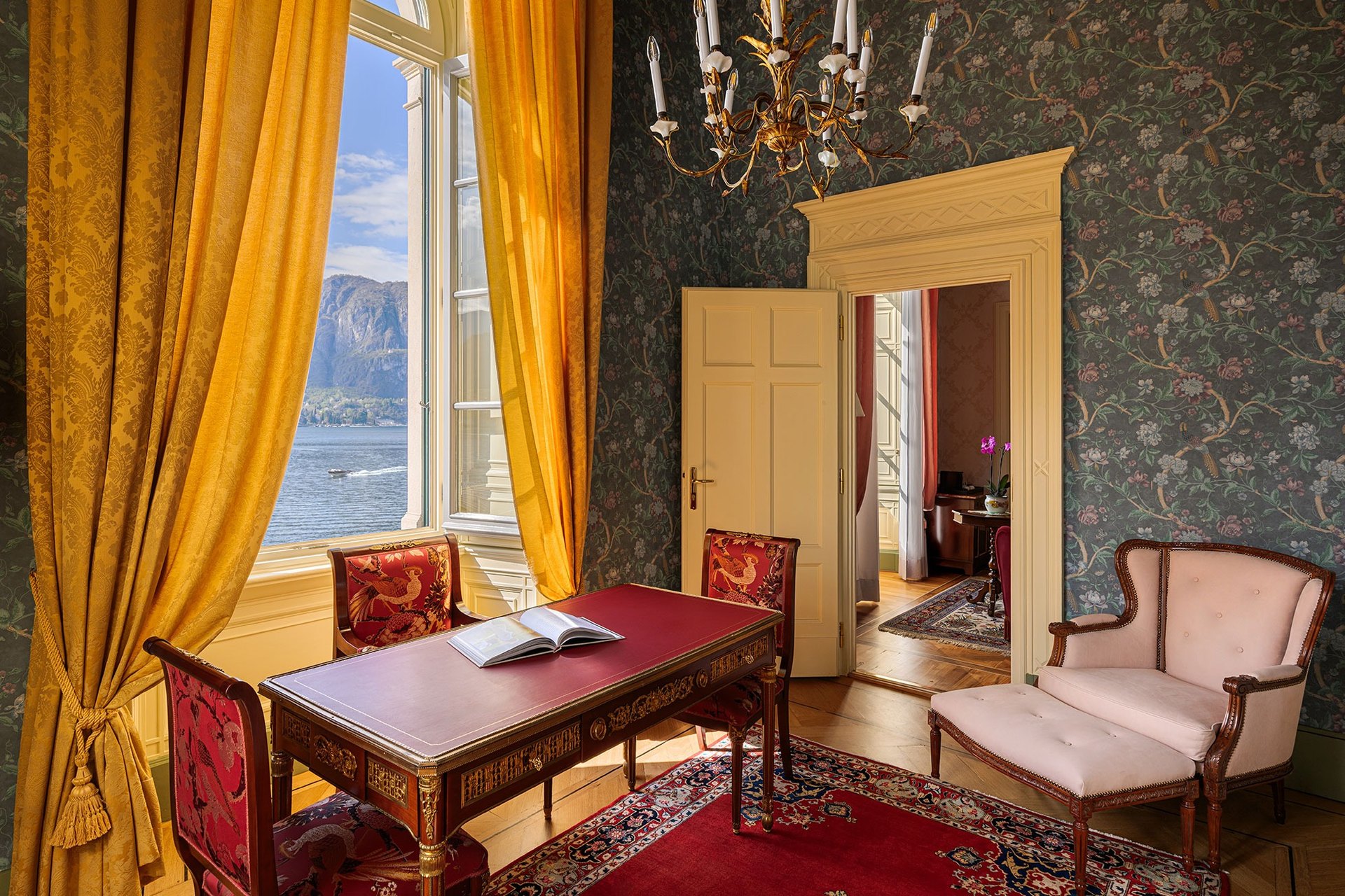 A suite at the Grand Hotel Villa Serbelloni: patterned wallpaper, gold curtains, a writing desk and a window onto the lake